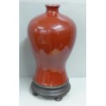 A Chinese sang de boeuf baluster vase and stand, large repaired crack to lower portion at base, 37cm