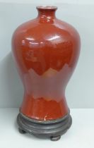 A Chinese sang de boeuf baluster vase and stand, large repaired crack to lower portion at base, 37cm