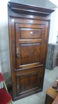 A George III stained pine freestanding corner cupboard