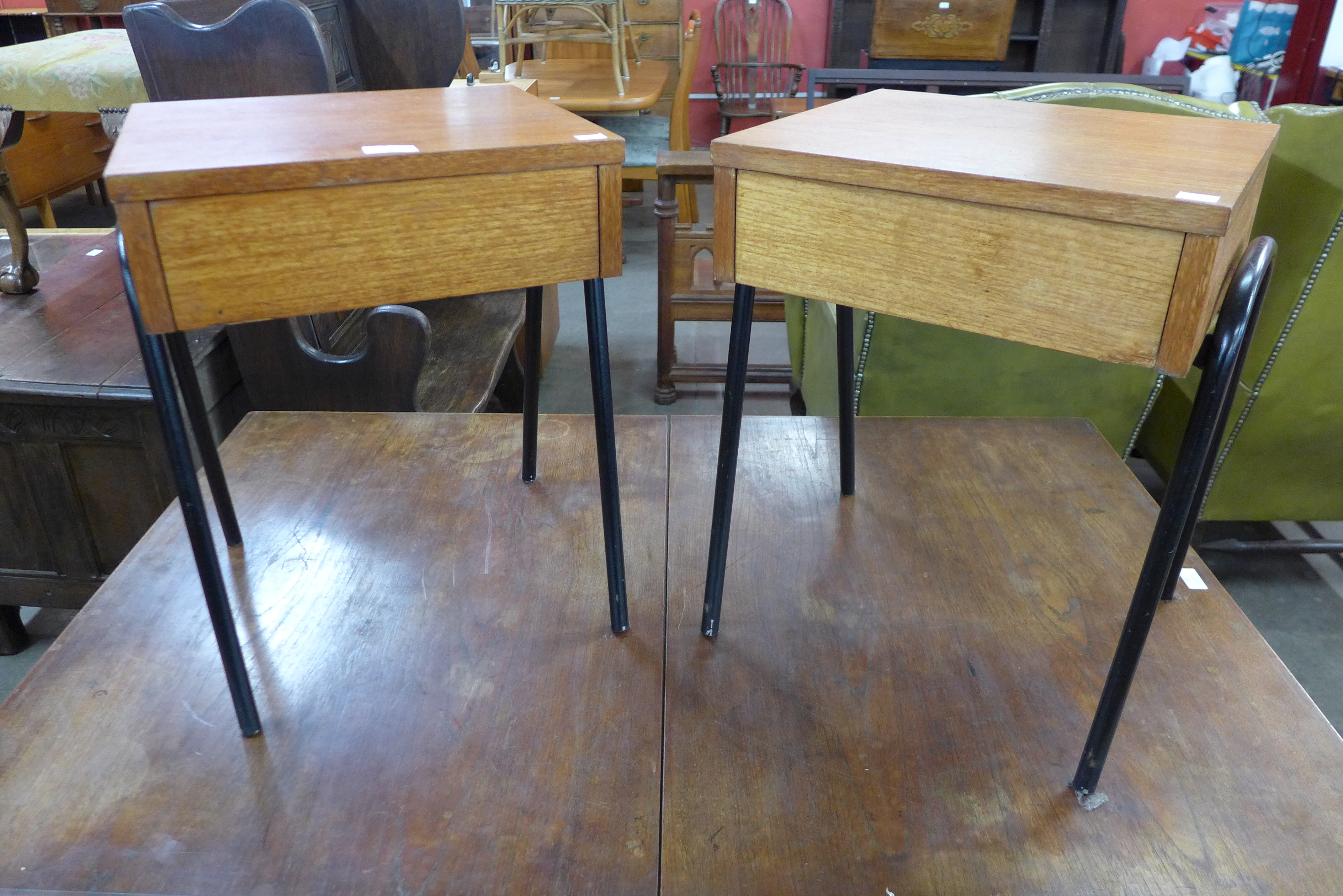 A pair of teak single drawer bedside tables, on black tubular metal stands