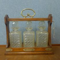 An early 20th Century oak and E.P.N.S mounted tantalus, with three glass decanters