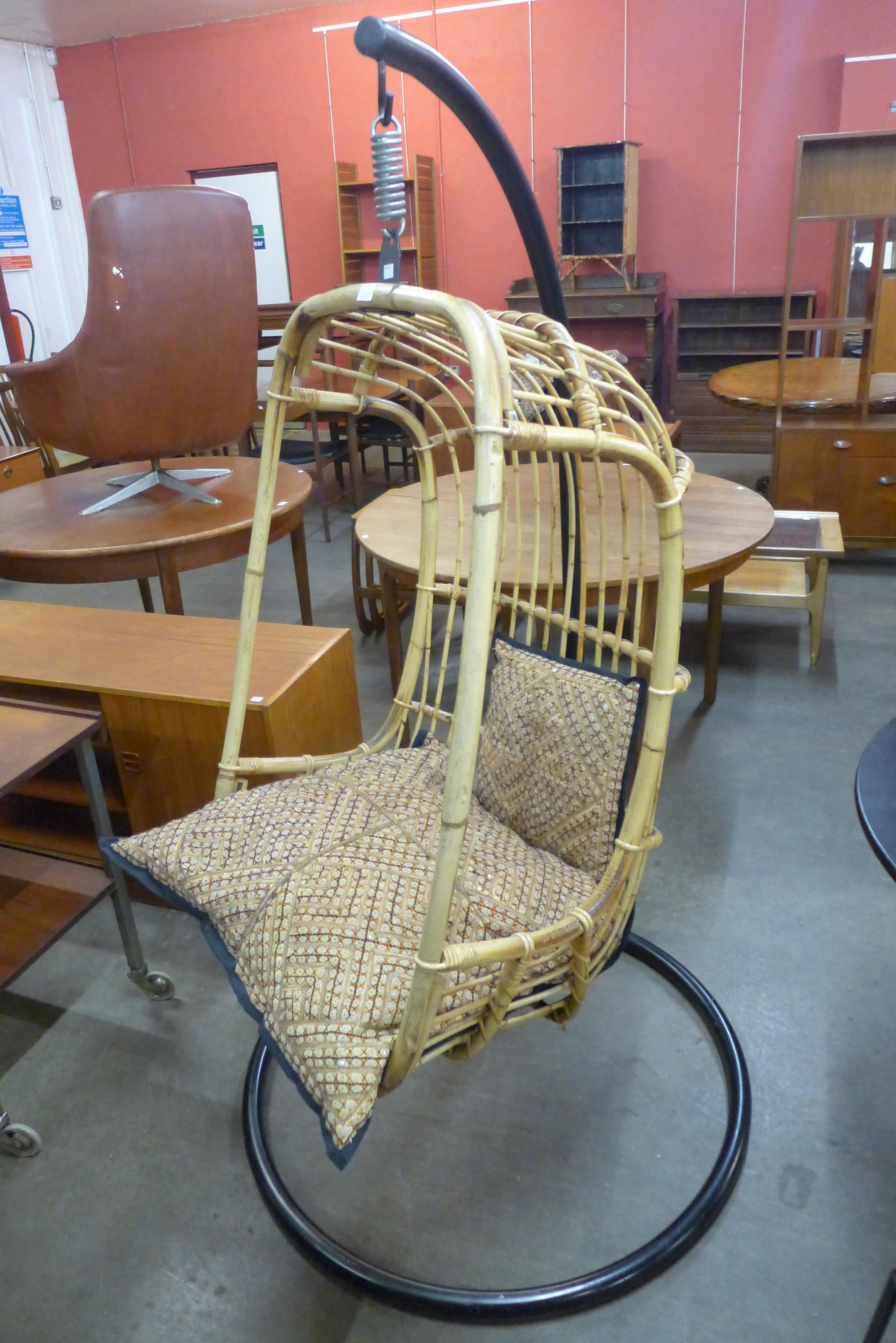 A bamboo hanging chair, on black steel stand