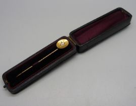 A yellow metal stick pin set with a diamond, 2.6g, cased