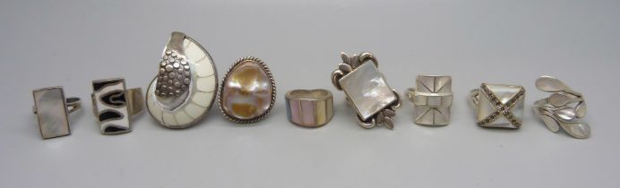 Eight chunky large silver rings set with mother of pearl, and one silver ring set with a fossil, 88g