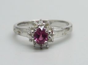 A 9ct white gold ring set with a garnet and white stone halo, 2.7g, N/O
