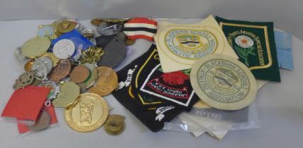 A collection of vintage athletic club badges, race medals and other badges and buttons