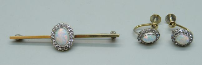 A gilt metal brooch set with a simulated opal and white stone cluster, and a pair of matching
