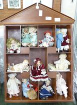 A doll display case with thirteen small china dolls and one other larger doll **PLEASE NOTE THIS LOT