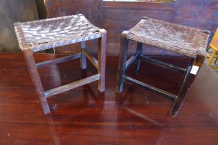 A pair of Arts and Crafts oak and leather strapwork stools