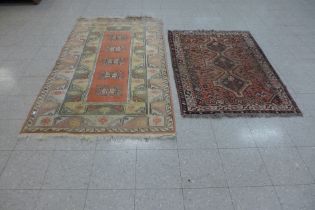 A terracotta ground rug and one other