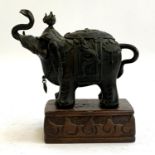 A Chinese bronze figure of an elephant in dragon adorned saddle, 13cmH, on a carved hardwood stand