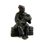 A bronze figure of a Chinese man holding a baby, seated on a pile of bamboo, 20cmH