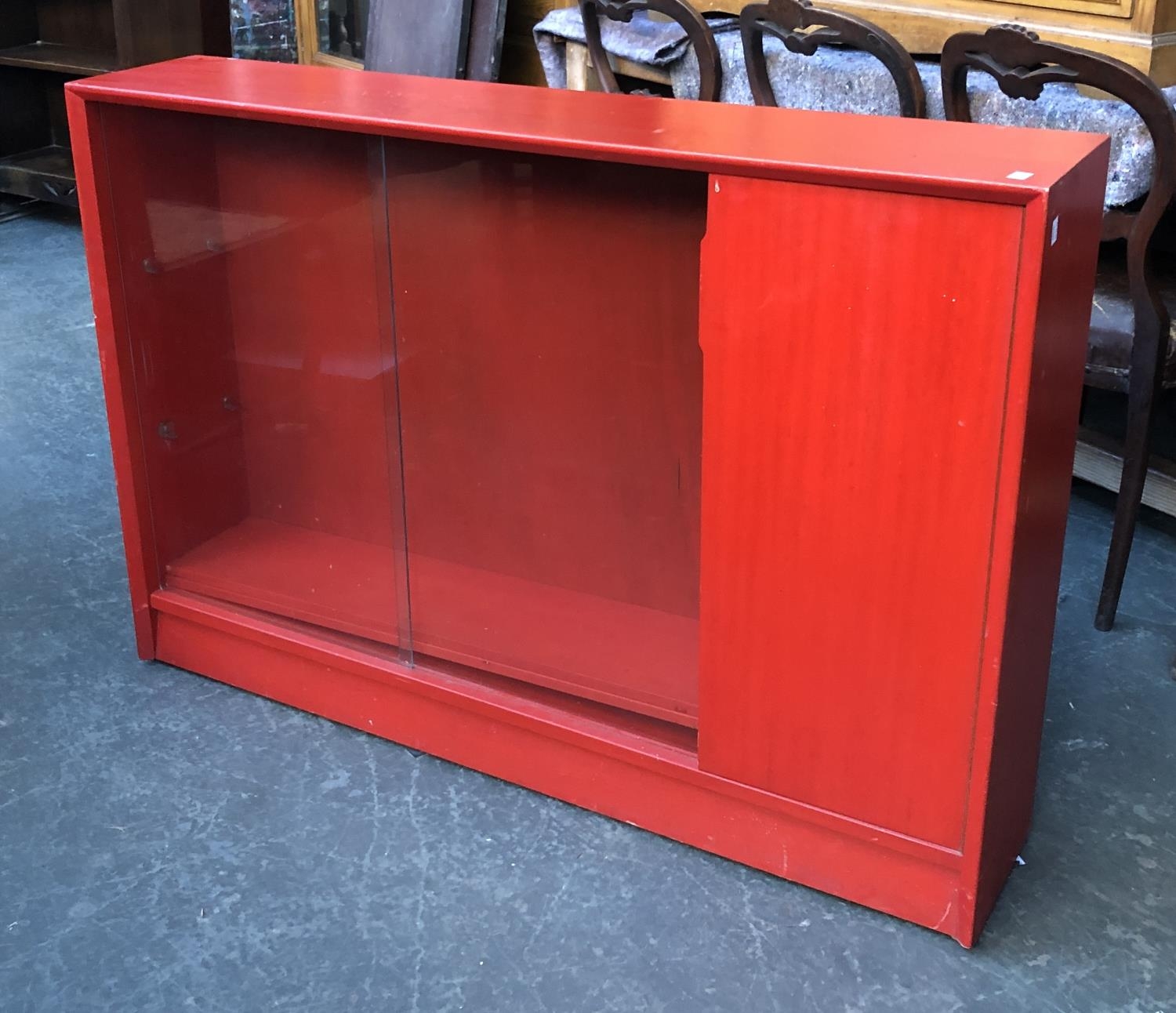 A mid century Gibbs glazed bookcase, stained red, having two sliding doors, 122x24x84cmH