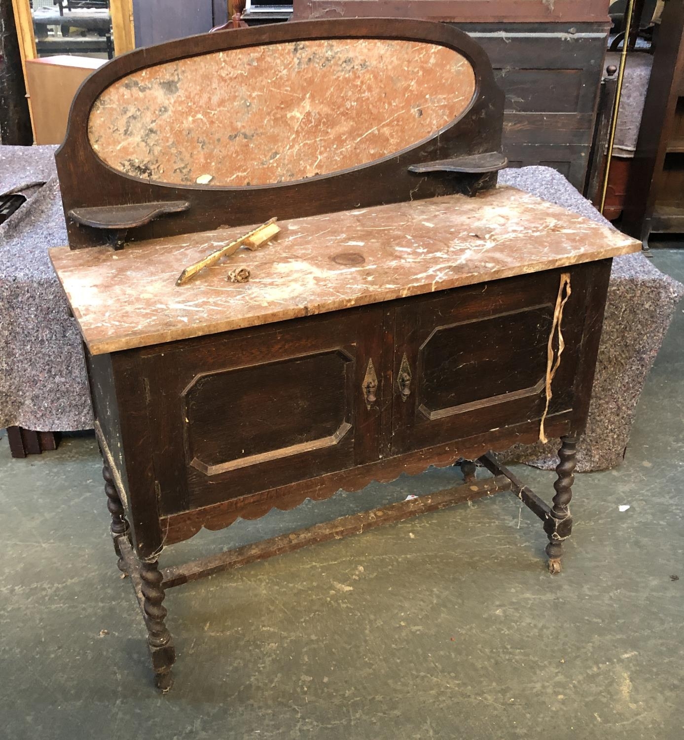 An early 20th century oak wash stand, marble top and upstand, over a pair of cupboard doors, on