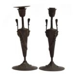 A pair of bronze candlesticks, decorated with masks of Bacchus and trailing hops, the base encircled