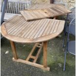 A slatted teak garden table, extending, with single spare leaf