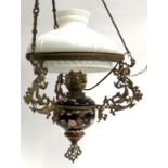 A hanging ceramic oil lamp with milk glass shade