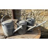 A 2 1/2 gallon galvanised metal watering can together with 2 others