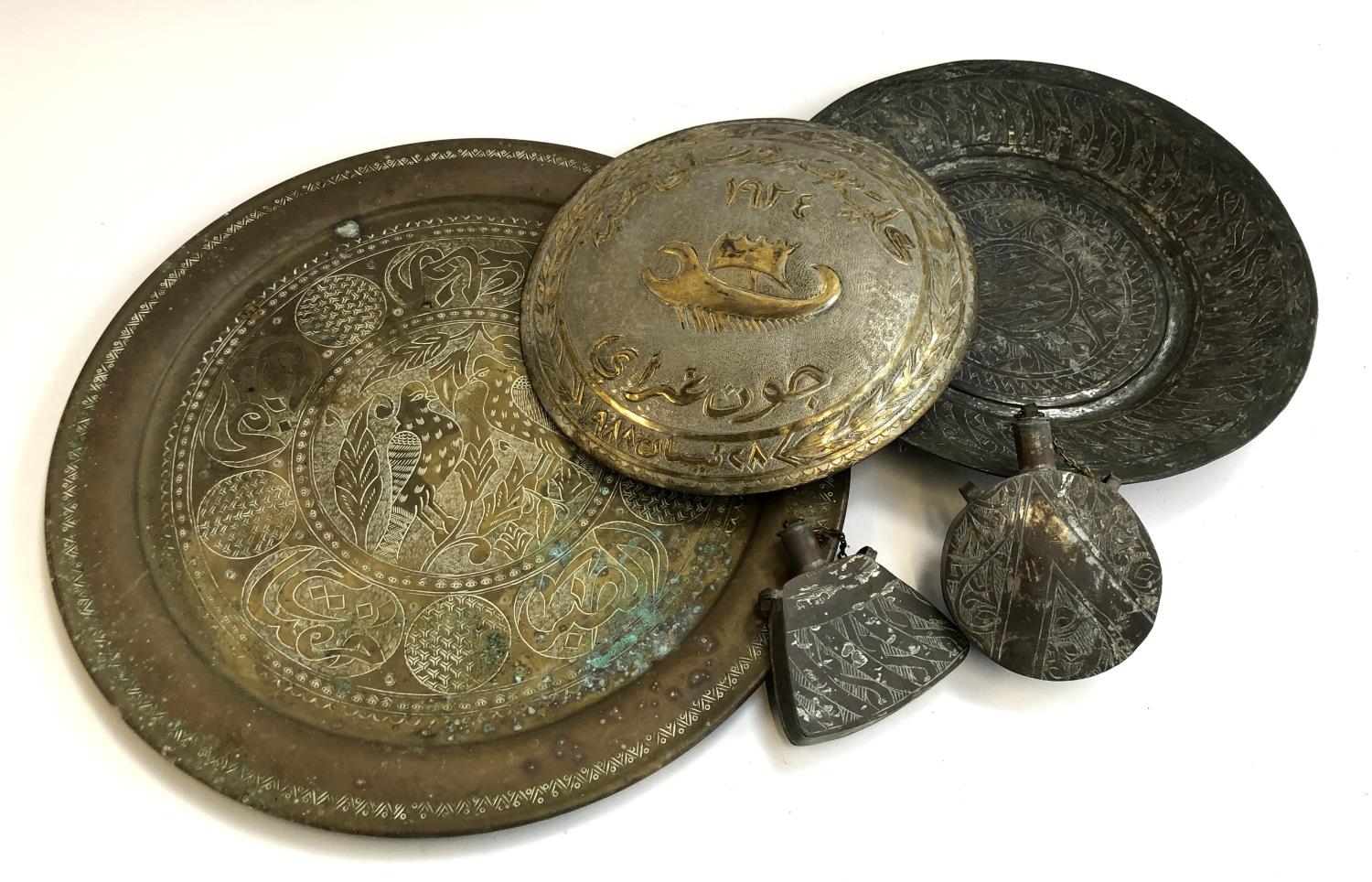 Two worked Islamic metal trays, 49cmW and 36cmW; together with a similar plaque and two flasks