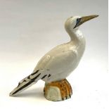 An Italian studio pottery bird (af), 35cmH; together with a carved wooden duck (2)