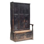 A provincial 18th century and later panelled hall settle and bacon cupboard, the seat with hinged