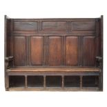 An 18th century oak tavern settle, the panelled back and sides over a two plank pine seat, on four