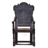 A Charles II oak wainscot chair, the shaped top rail carved with a tree motif, the back panel with