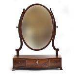 A George III mahogany and line inlaid oval dressing mirror, on a serpentine base of three drawers,