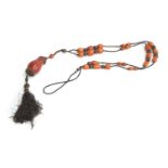 An amber bead necklace, on knotted cord with silver studded coral beads, tassel hanging from a large