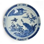 A Chinese export blue and white porcelain charger, decorated with a scene of a peacock and sparrow