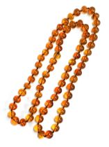 A long string of amber beads, knotted, each bead approx. 1.4cmW, one bead cracked, approx. 95g, 50cm