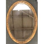 A gilt gesso mirror with oval bevelled glass plate, 91x65cm