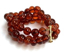 A three row amber bead bracelet, with sliding clasp stamped 14/20, 58g