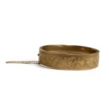 A Victorian 9ct gold bangle, engraved with leaves, hallmarked for Birmingham 1886, with safety