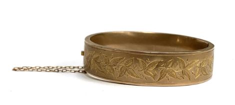 A Victorian 9ct gold bangle, engraved with leaves, hallmarked for Birmingham 1886, with safety