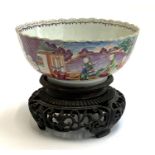 A Chinese famille style fruit bowl with scalloped edge, 23cmD on a carved hardwood stand (af)