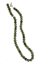 A Chinese jade bead necklace, the beads approx. 0.7cmD, in need of restringing, with a white metal