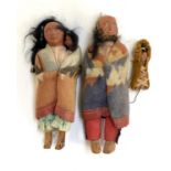 A pair of dolls in the form of Native Americans carrying babies, one with face af