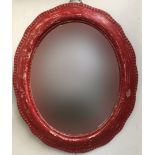 A red painted oval wall mirror with wavy edged frame, 67x54cm
