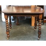 An early 20th century extending oak dining table, with spare leaf and winder, on bobbin turned