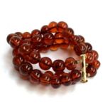 A three row amber bead bracelet, with sliding clasp stamped 14/20, 58g