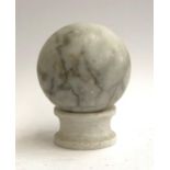 A white marble orb, 15cmD, on a turned alabaster socle