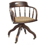 An early 20th century oak adjustable swivel office chair, on brass casters, 54cmW