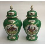 A pair of large porcelain urns, painted with panels of fancy birds on a green ground, heightened