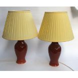 A pair of brick glazed baluster form table lamps with yellow pleated shades, 65cmH to top of shade