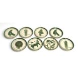 A set of eight hand painted plates decorated with various green vegetables including asparagus,