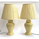 A pair of yellow baluster form table lamps with pleated yellow silk shades, 69.5cmH to top of shade