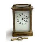 A brass carriage clock with bevelled glass and enamel dial with Roman numerals, 11cmH, with key