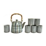 A Japanese ceramic tea set with striped design, six cups and a teapot with bamboo handle