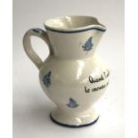 A French faience jug, hand painted with blue floral motifs and the motto 'Quand l'estomac joue du